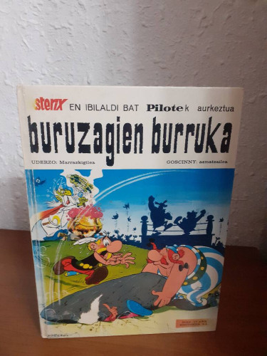 Portada del libro de ASTERIX EN IBILALDI BAT PILOTEK AURKEZTUA BURUZAGIEN BURRUKA